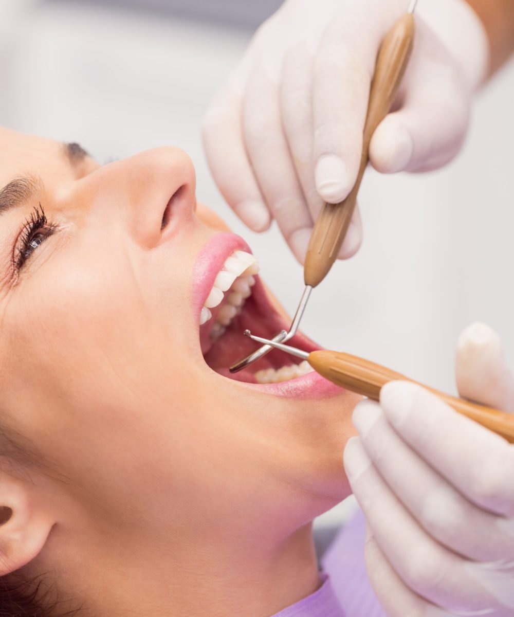 dentista-examinando-dientes-paciente-femenino-scaled.jpg